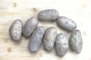 Eight raw potatoes on a wooden surface, perfect for rustic kitchen decor or recipe ideas.